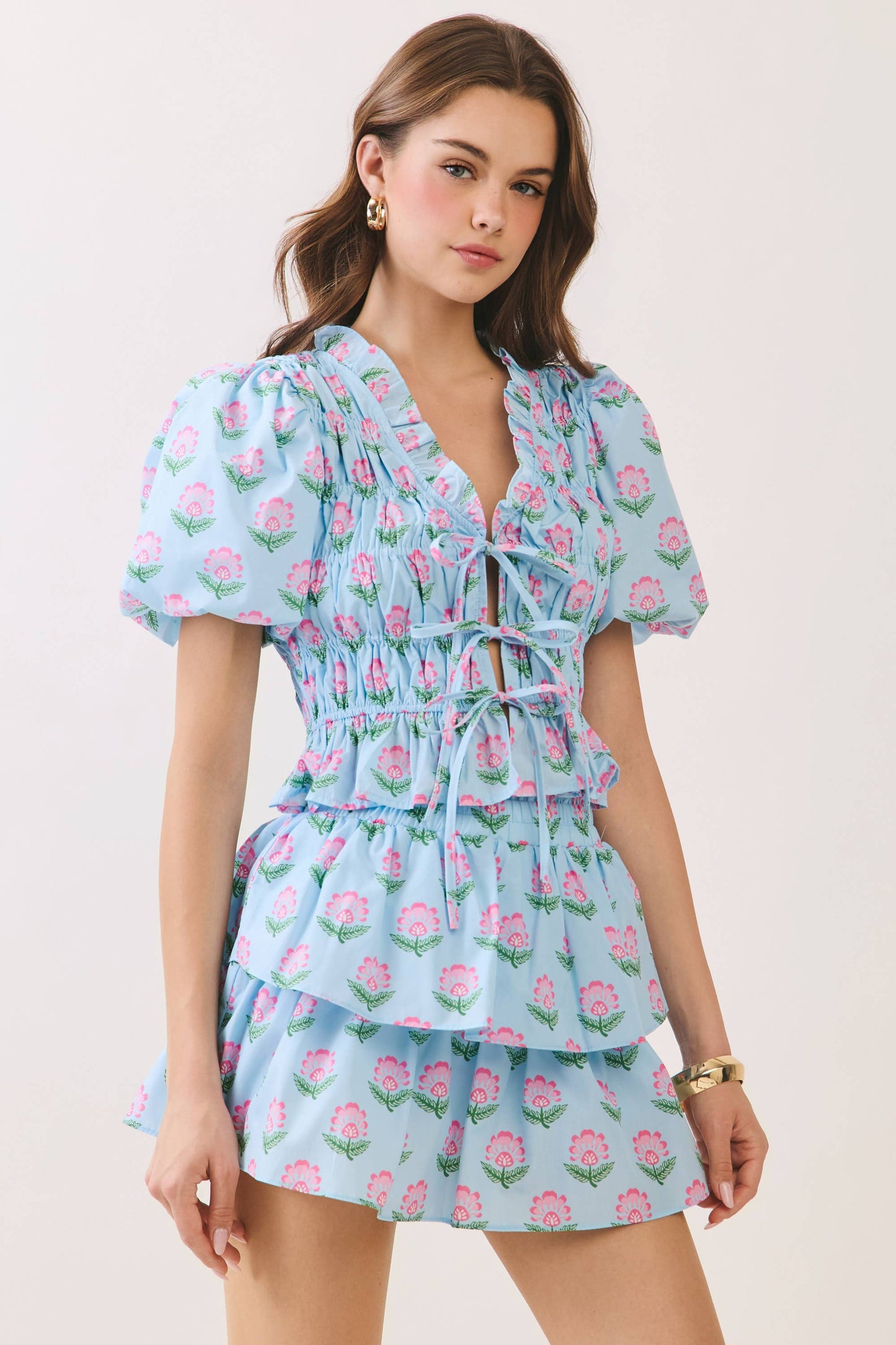 Woman wearing a light blue floral dress against a plain background