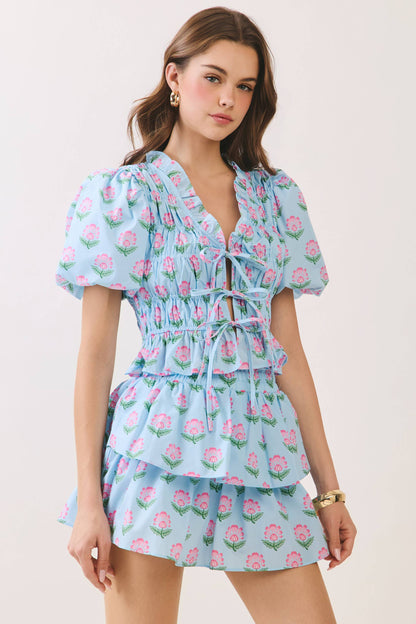 Woman wearing a light blue floral dress against a plain background